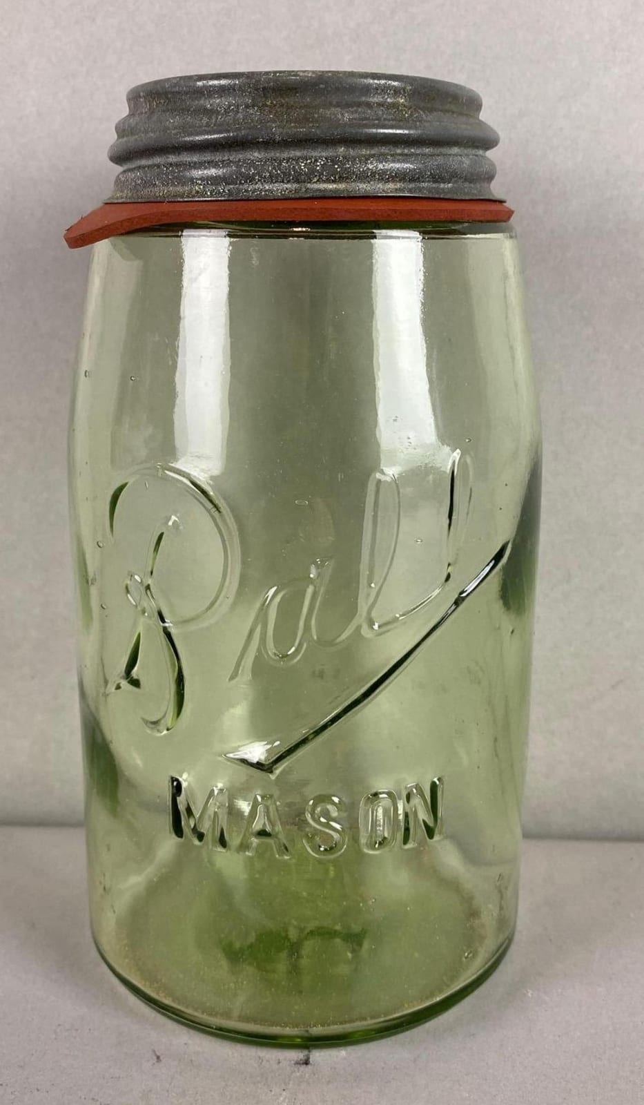Green glass ball mason jar with black metal lid and embossed “Ball” and “Refrigerator” lettering.