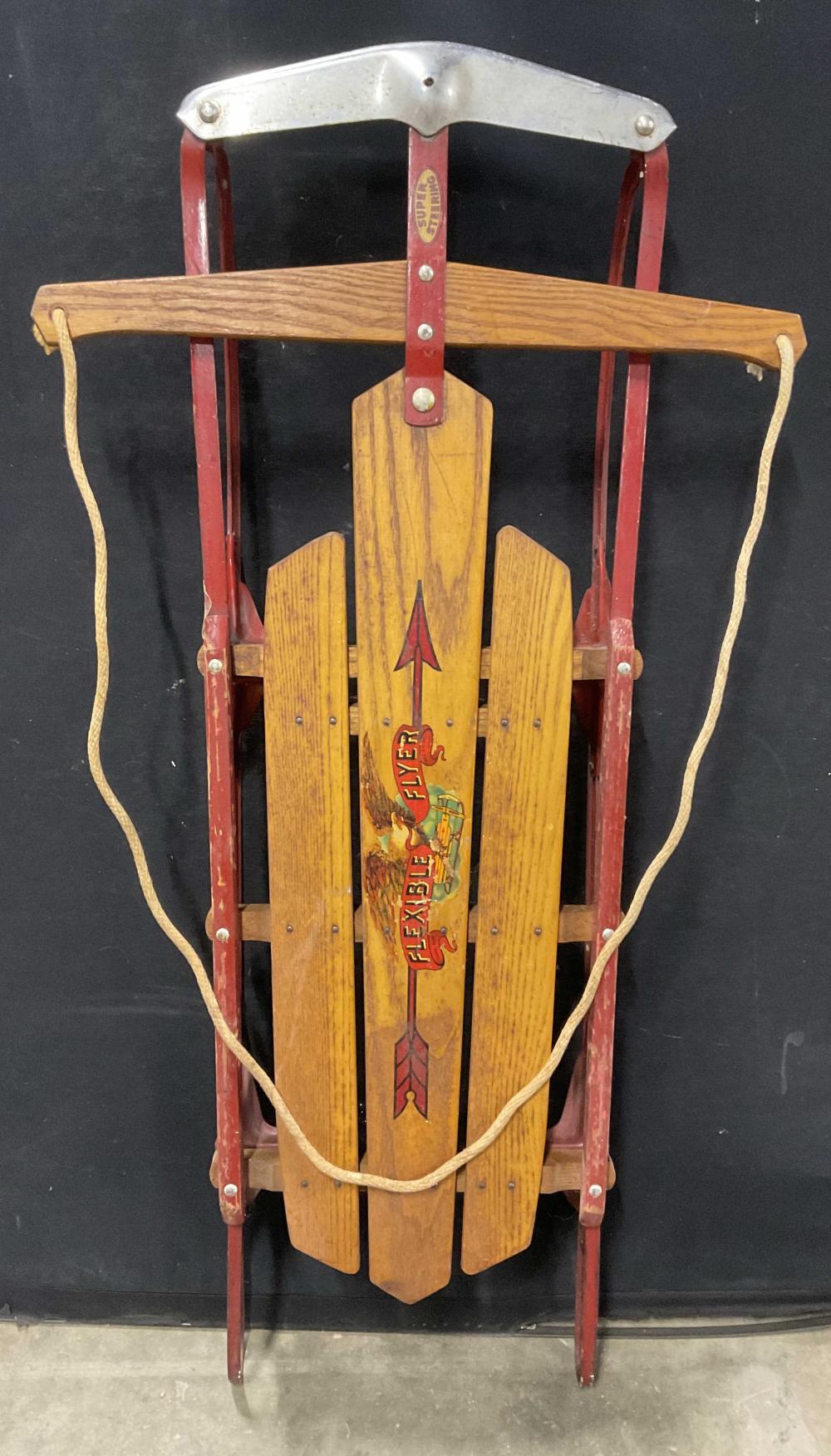 Vintage wooden sled with red metal runners and a central banner reading “Super Steering Flyer 41H”.