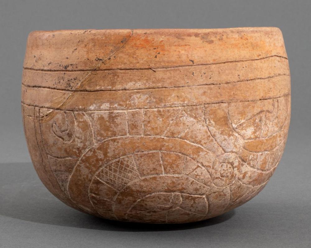 Terracotta pottery bowl with incised geometric and animal-like designs, viewed from the side.