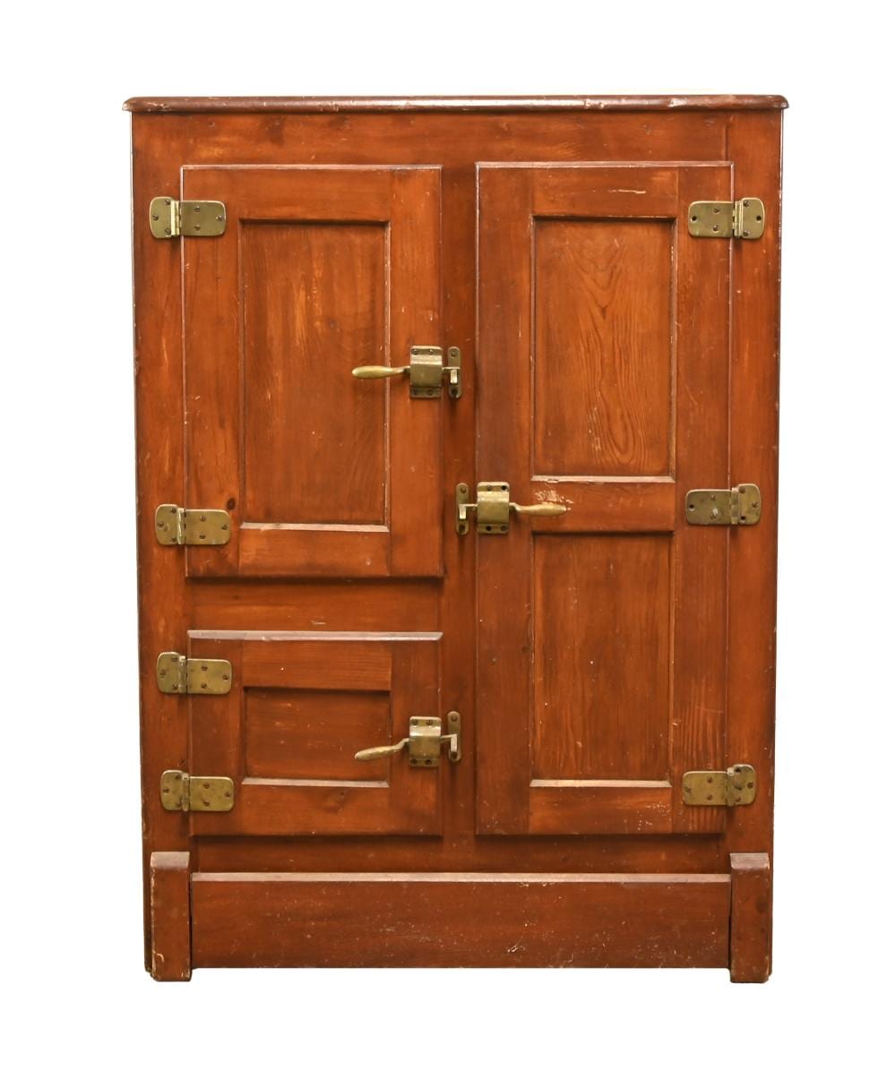Front view of a brown wooden cabinet-style ice box refrigerator with three doors and brass hinges and latches.