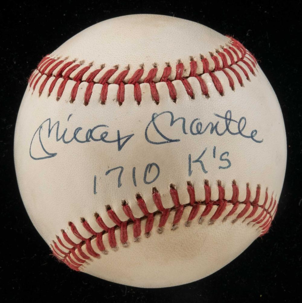 Close-up of a signed baseball with blue ink signature “Mickey Mantle,” “1710 K’s” and an inscription on a black background.