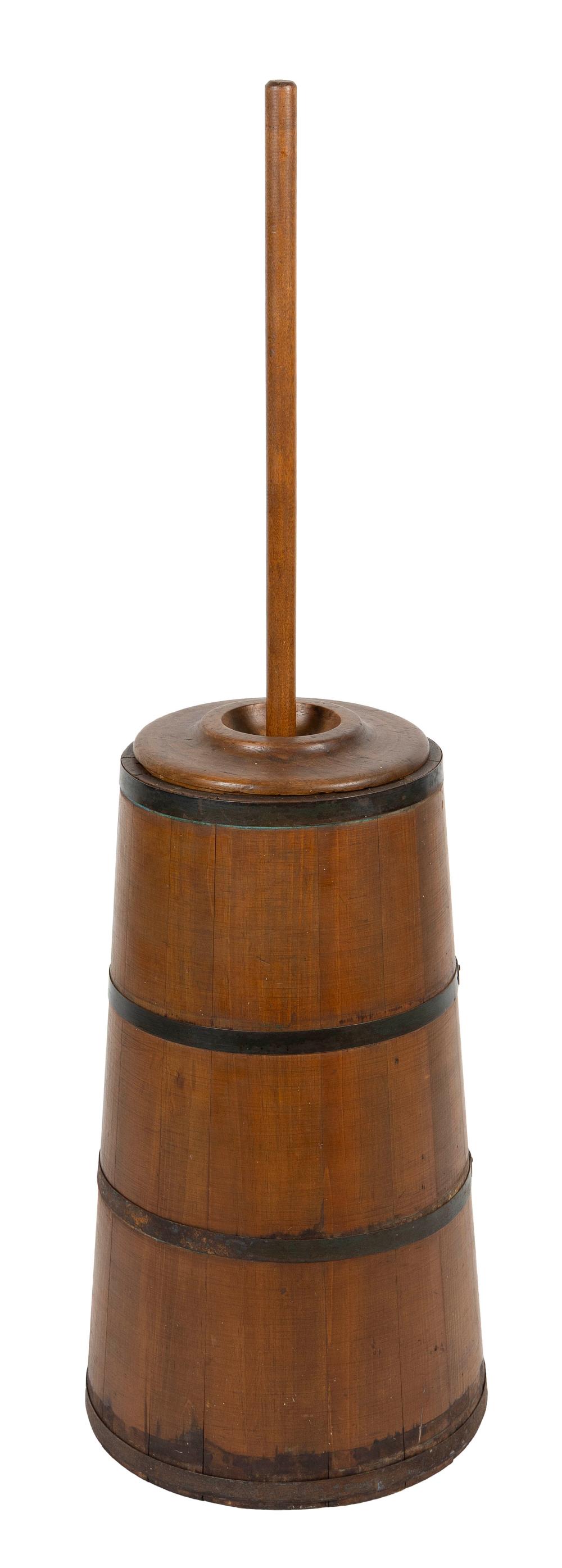 Wooden butter churn with a vertical dasher and dark iron bands around the barrel.