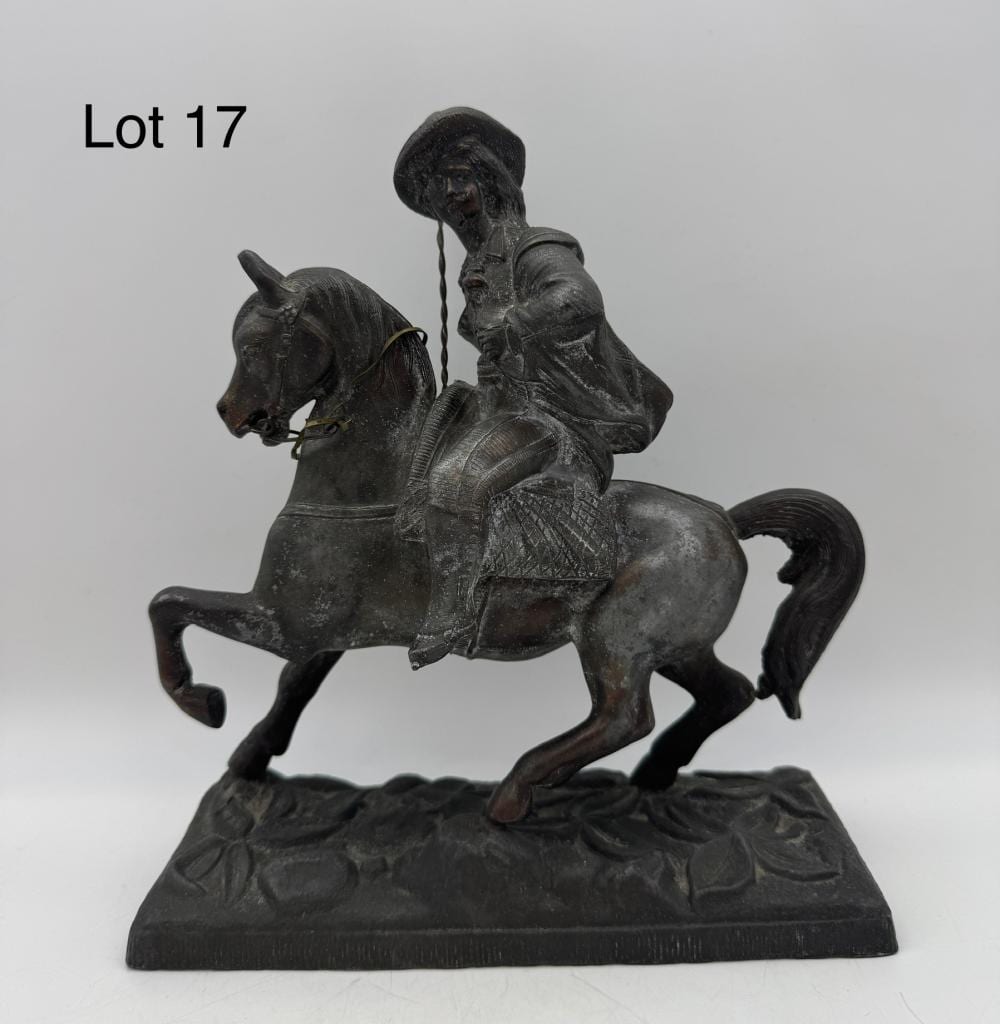 Bronze-tone figurine of a cowboy riding a rearing horse, posed on a flat base with engraved-looking details.