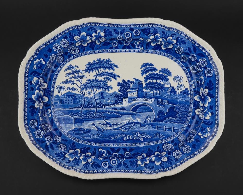 Oval white serving platter with blue and white transfer-print landscape scene and floral border.