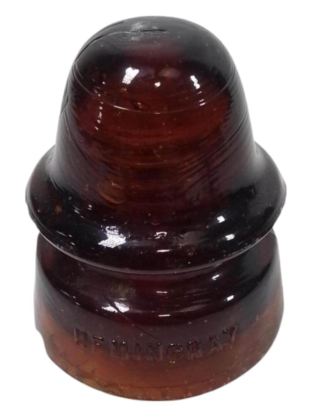 Dark amber glass insulator shaped with a rounded top and flared base, with molded markings near the bottom.