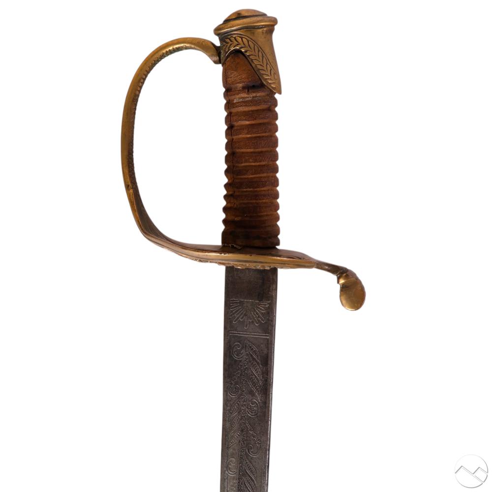 Close-up of a Civil War style officer sword with a carved wooden grip and engraved metal blade, shown upright against a white background.