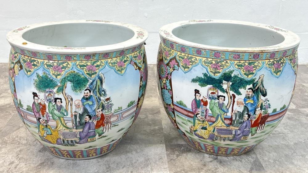 Pair of large Chinese-style fishbowl planters with blue ground and colorful painted figures and trees on the sides.