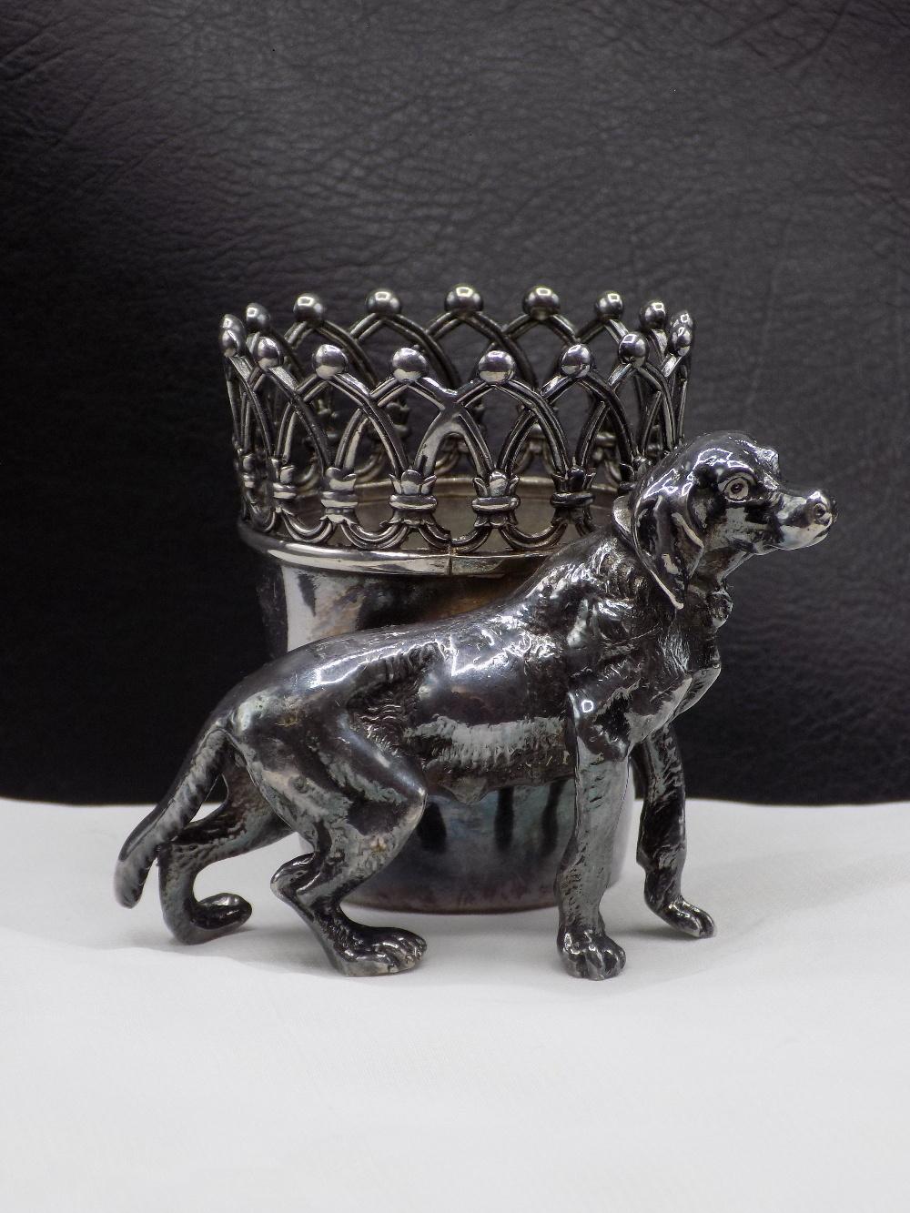 Silver-colored dog figurine holding a toothpick holder with pierced crown-like top and carved curves.