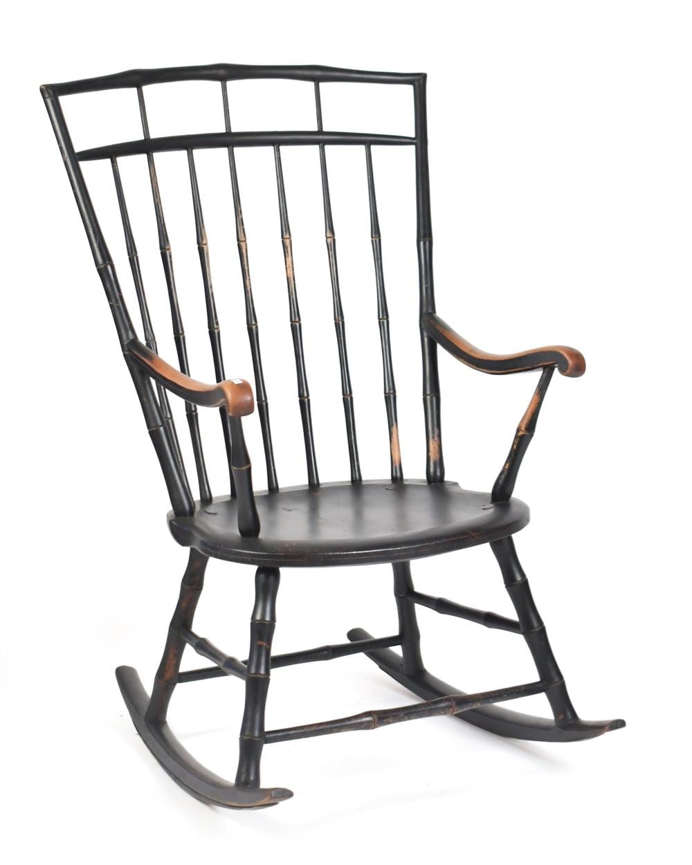 Wooden Windsor rocking chair with spindle back, curved arms, and dark finish on a white background.
