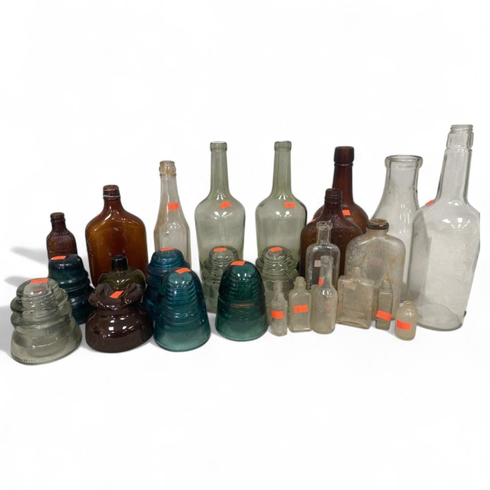 Collection of vintage glass bottles and insulators in various colors, arranged in a row on a white background.