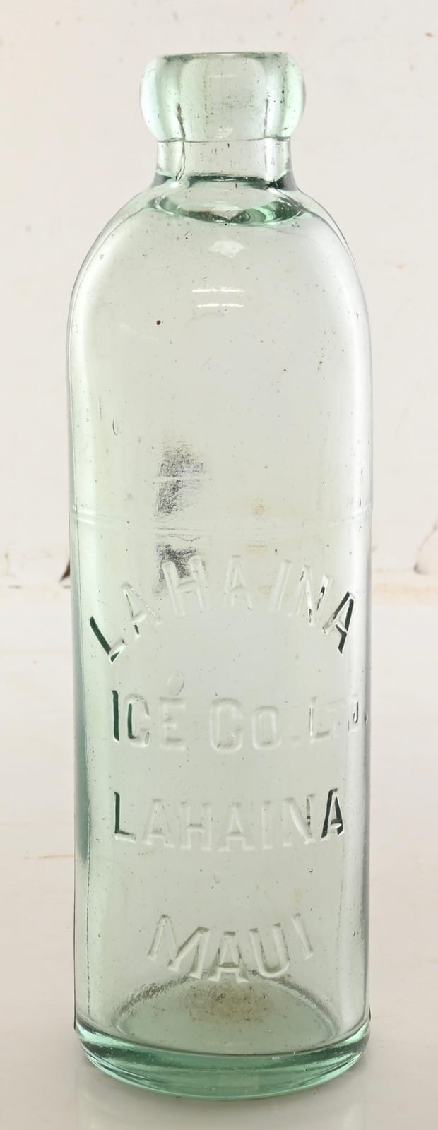Clear glass soda bottle with a rounded “blob” top and embossed text, viewed against a light background.