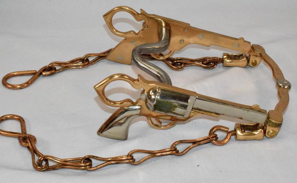 Close-up of a brass-and-steel horse bit curb bit with spiked mouthpiece, attached to metal chains.