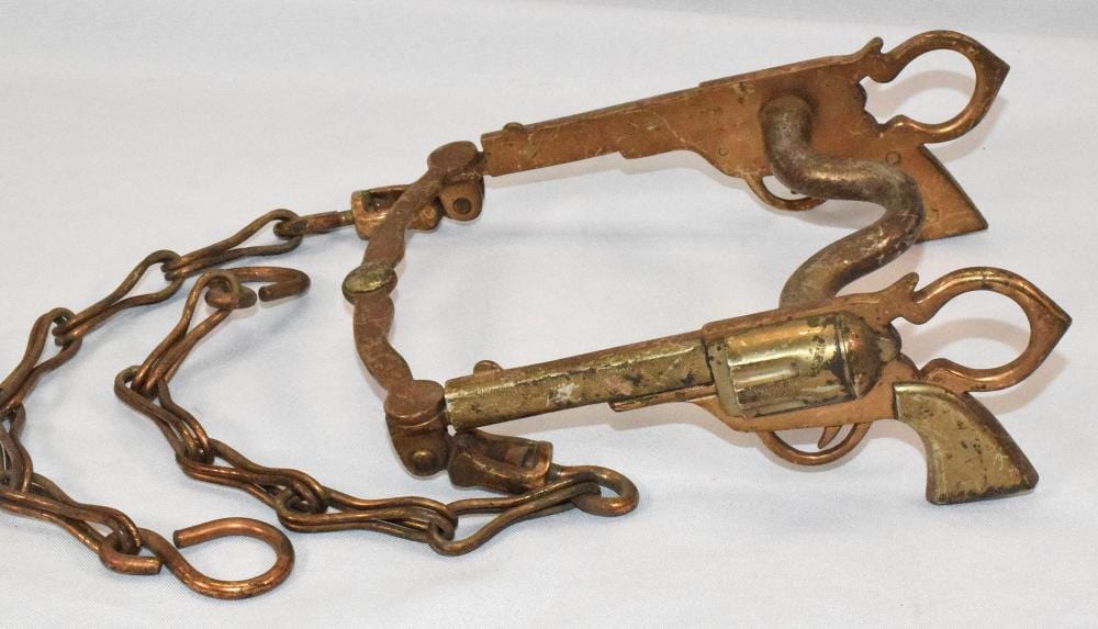 Bronze-colored horse curb bit with articulated hardware and a short handle-like center section, shown with a linked chain on a white background.