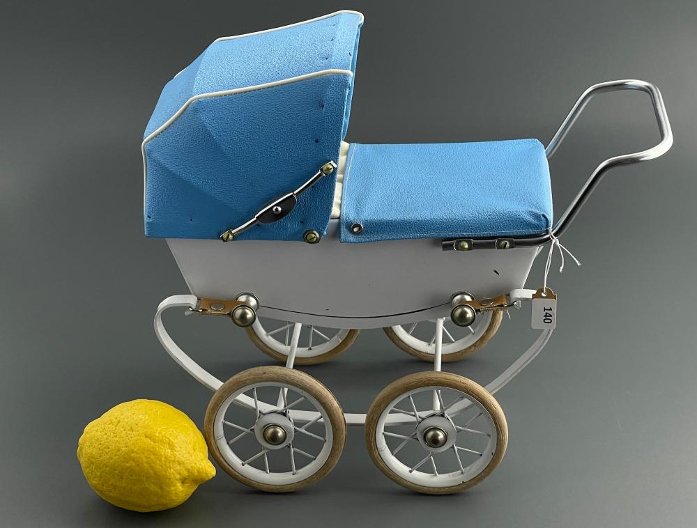 Miniature blue doll carriage with a white wheel frame and metal handle, shown against a gray background.