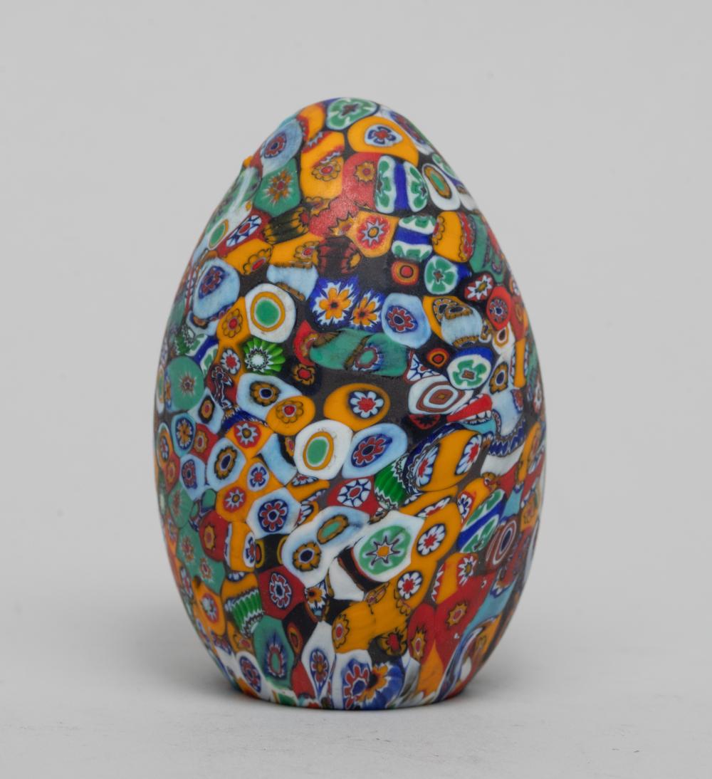 Close-up of a multicolored millefiori glass paperweight with many small patterned glass beads under a clear dome.