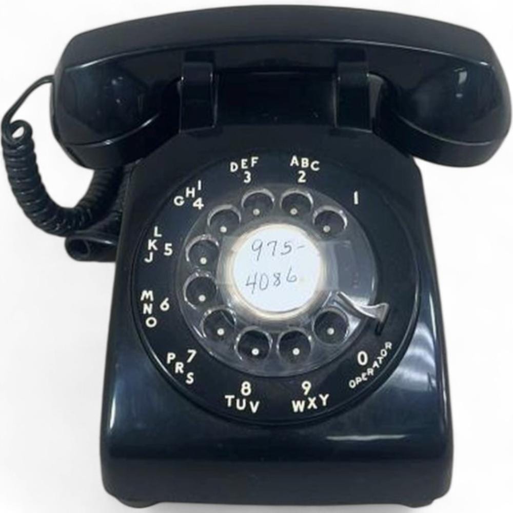 Black rotary dial desk telephone with handset, showing numbered letter ring and rotary dial face.