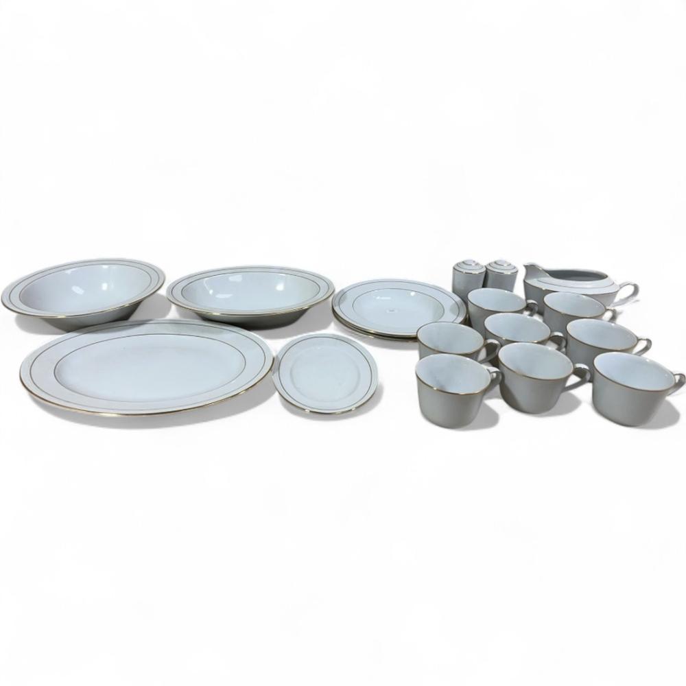 Set of white dinnerware with light blue rims: oval plates, round plates, small bowls, cups, and a creamer with sugar bowls on a white background.