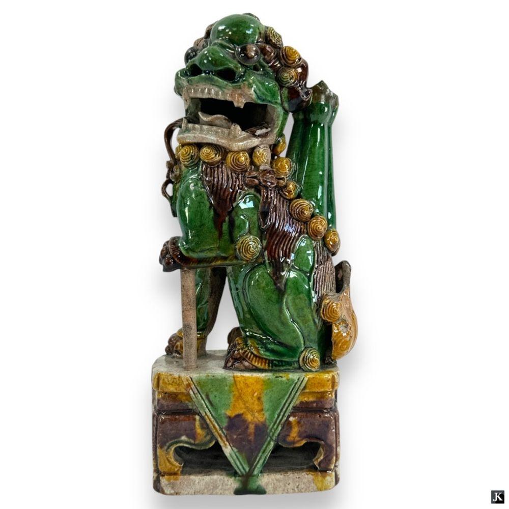 Green glazed ceramic foo dog figure with gold spiral details and a curled mane, standing on a decorated base.