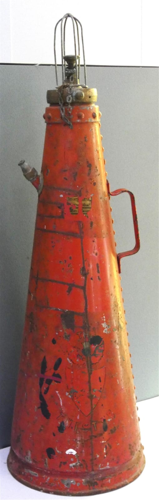 Red vintage-style fire extinguisher with a metal top handle and curved hose, photographed against a light background.