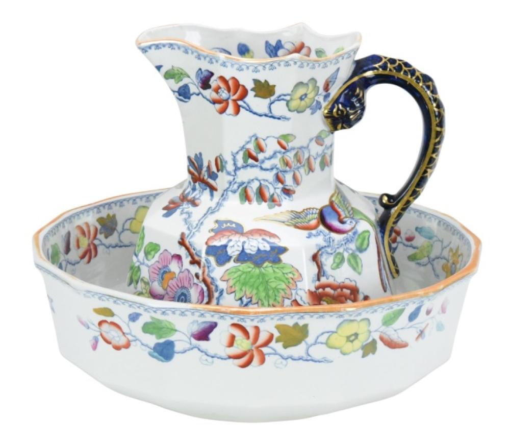 White ceramic wash basin with floral and butterfly pattern and a matching pitcher with ornate blue-and-gold handle.