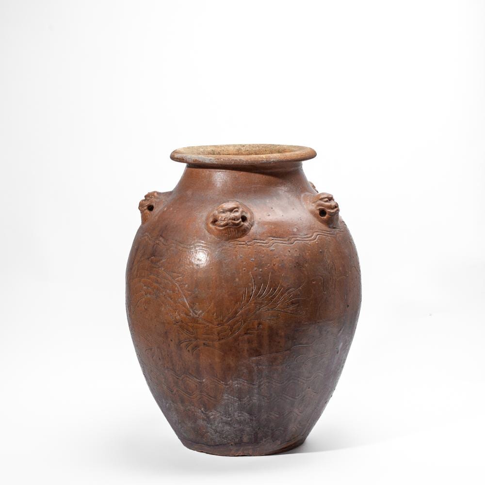 Brown ceramic jar with rounded shoulders, a wide mouth rim, and molded animal face handles on both sides, decorated with floral scroll motifs.