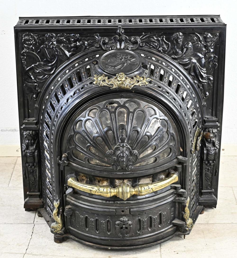Front view of an antique-style cast iron stove with decorative relief panels, ornate circular firebox door, and brass-colored trim.