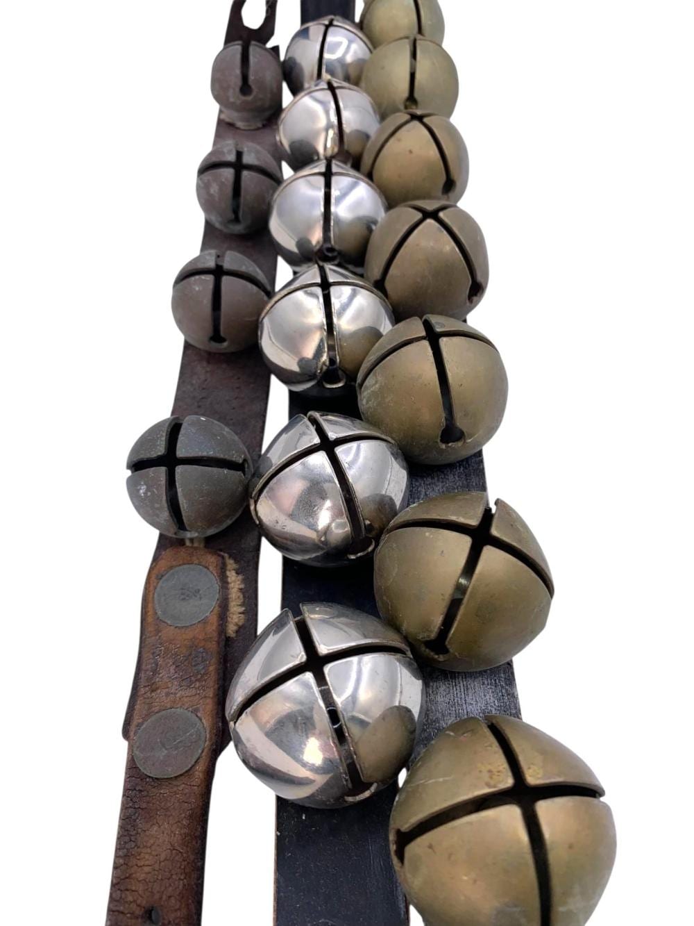 Close-up of a cluster of horse sleigh bells attached to leather straps, with chrome and brass colored bells.