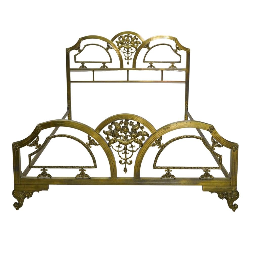 Antique-style brass bed frame headboard and footboard with ornate arched metal panels and decorative finials.