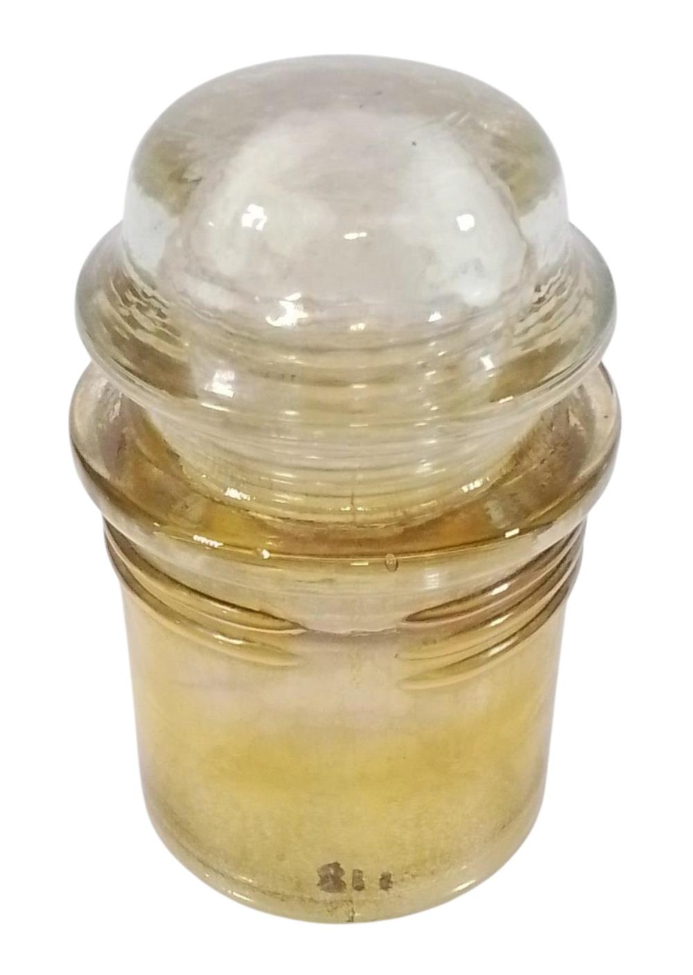 Close-up of a clear glass insulator with a rounded dome top and ribbed banding around the middle, amber-tinted body.