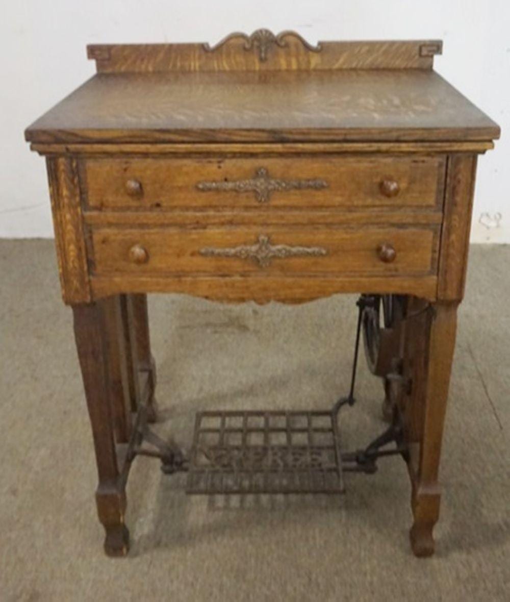 Wooden cabinet-style treadle sewing machine with two front drawers and decorative metal pulls.