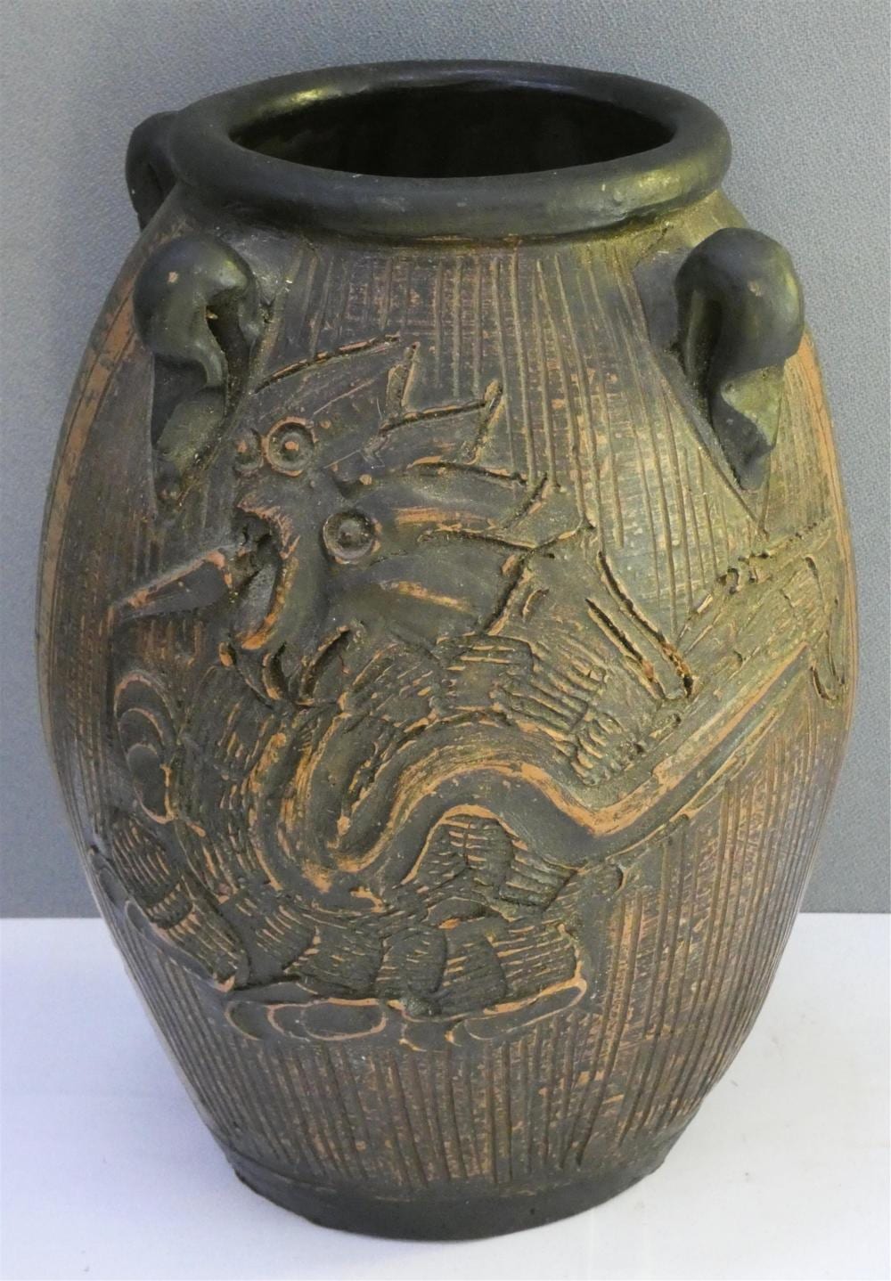 Antique-looking dark ceramic jar with a wide mouth and ornate painted bird and floral designs around the body.