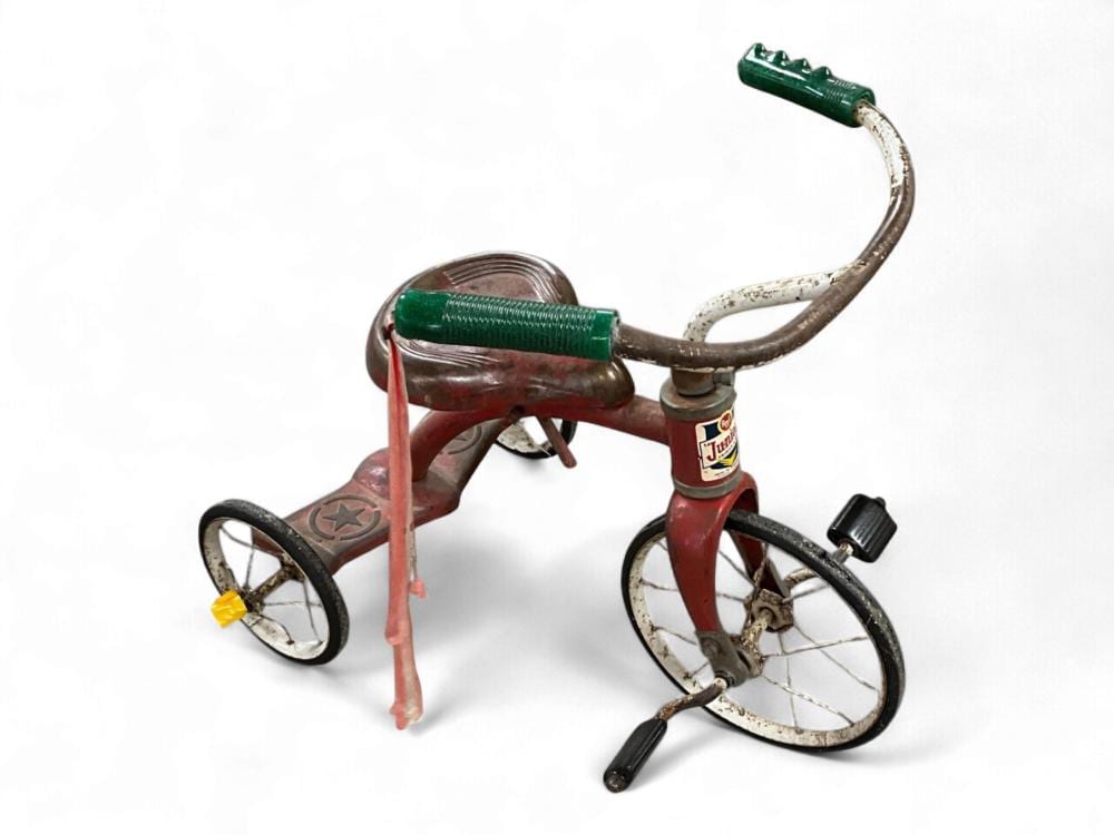 Small red and dark green toy tricycle with three wheels, curved handlebar, and a front bell or horn on a white background.