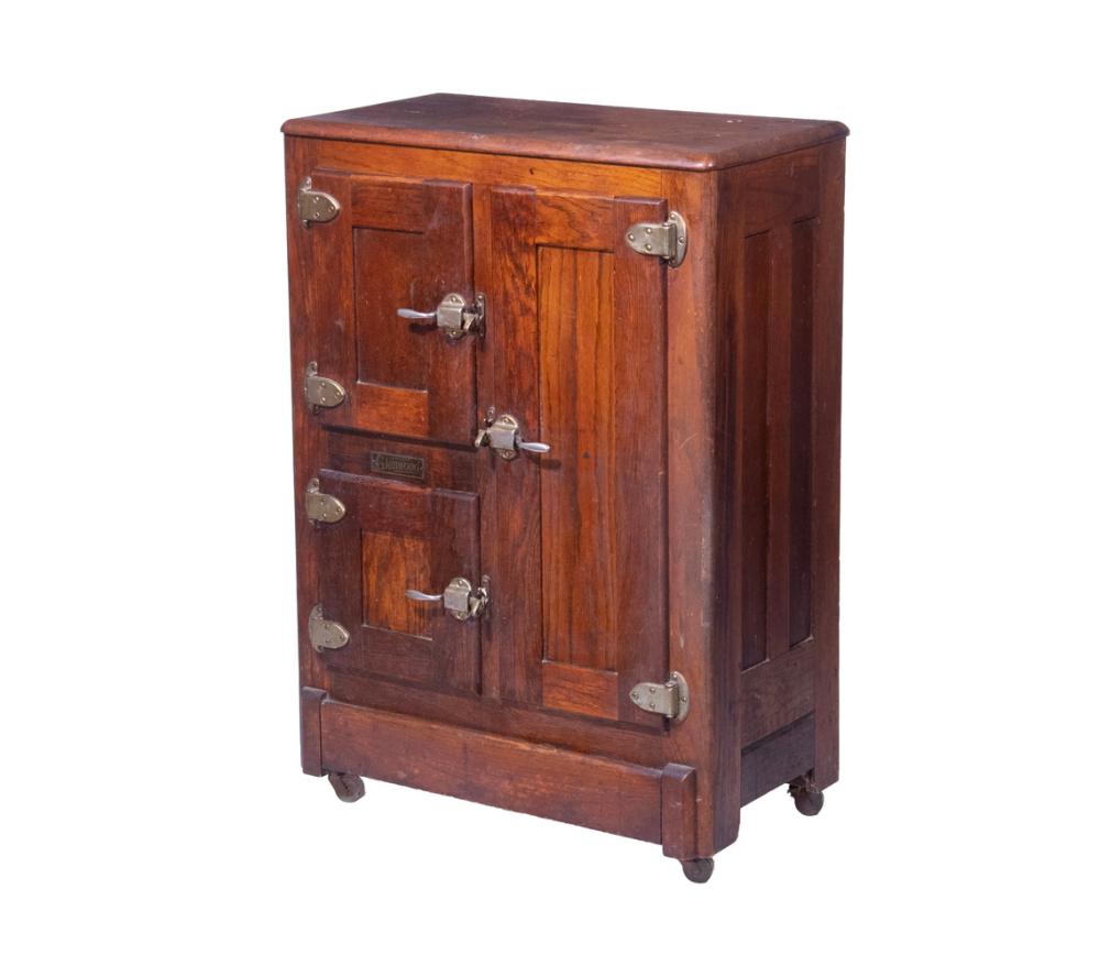 Antique wooden ice box with a hinged lid and multiple front doors, metal latches, and four small caster feet.