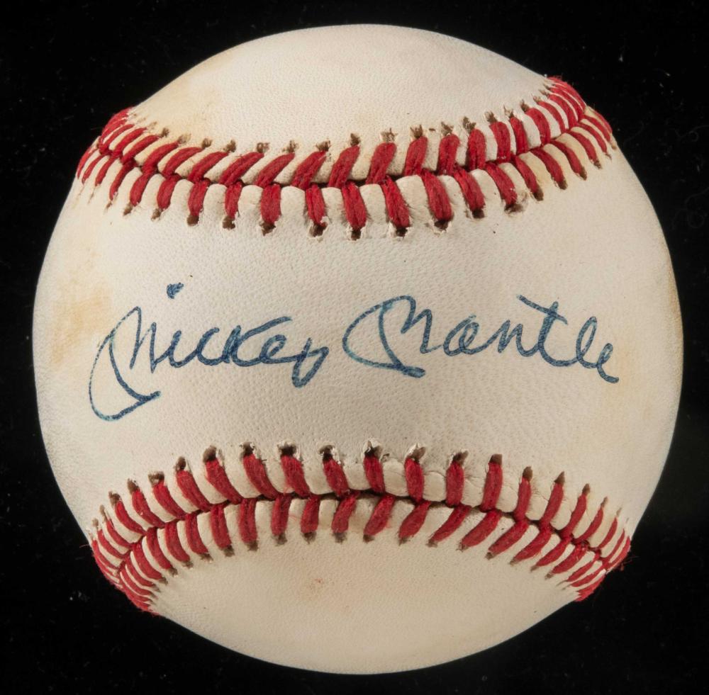 White baseball with red stitching and blue handwritten signature reading “Mickey Mantle” on a dark background.