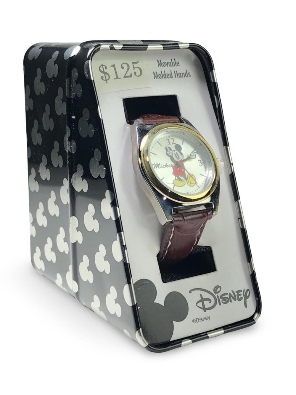 Mickey Mouse themed wristwatch with round silver case, brown leather strap, and Mickey graphic dial inside a display package.