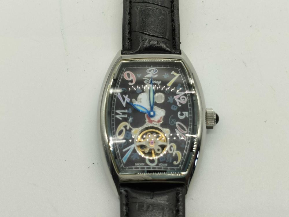 Black leather strap Mickey Mouse themed wristwatch with colorful dial and visible crown on the right side.
