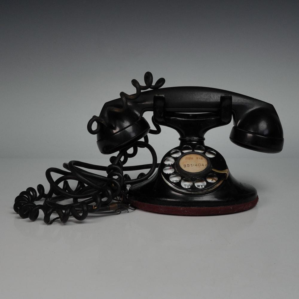 Vintage rotary telephone with black handset and base on a white background, showing the dial and coiled cord.