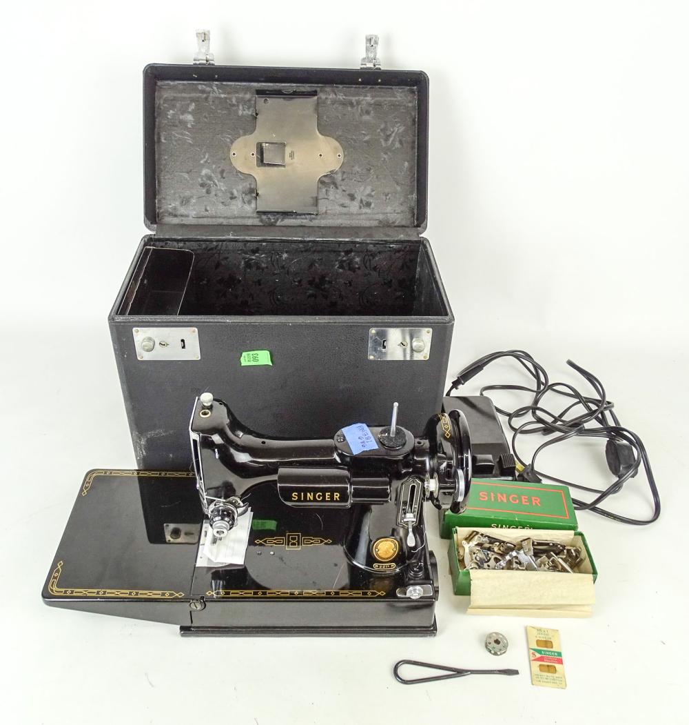 Black vintage Singer Featherweight sewing machine shown open with case, accessories, and cords on a white background.
