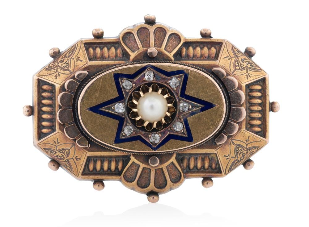 Gold-tone brooch with a round pearl center, surrounded by a blue star setting and small faceted stones.