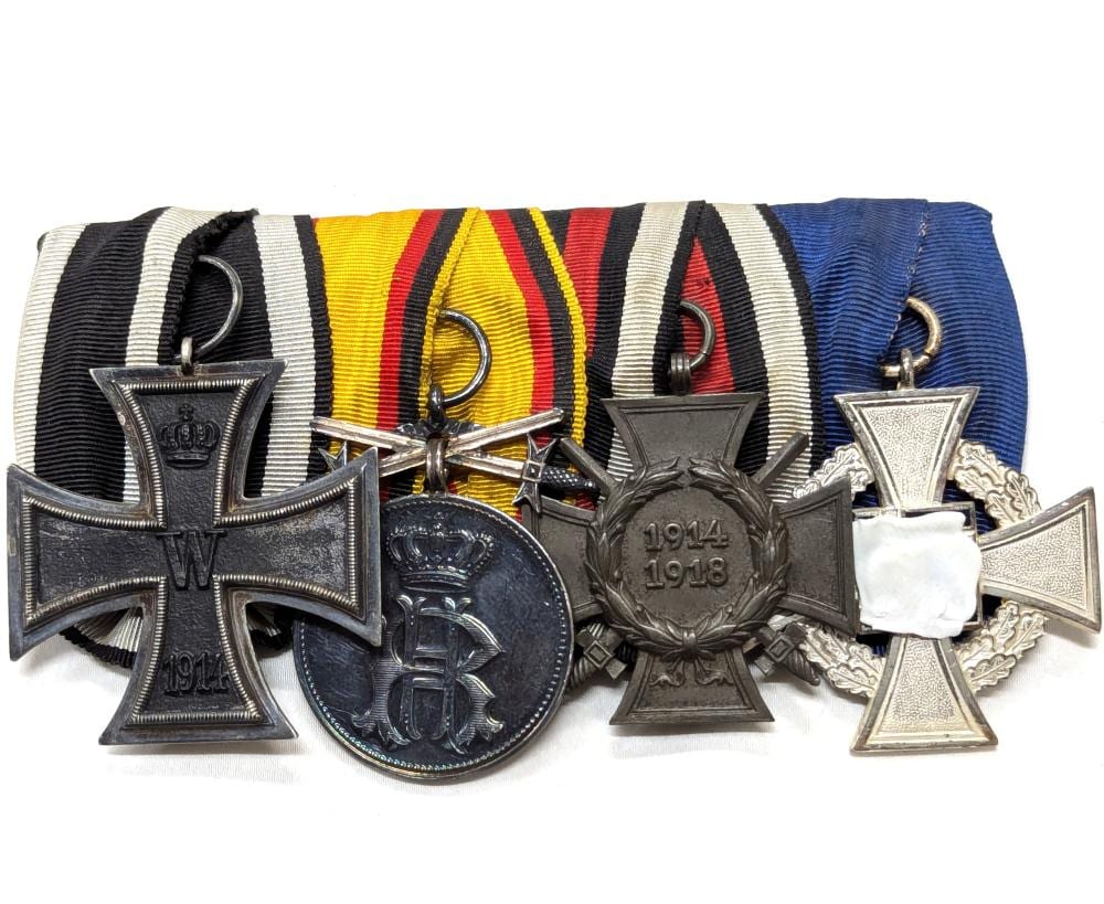 Group of German style World War medal crosses and circular medal with ribbons in black, yellow, red, and blue