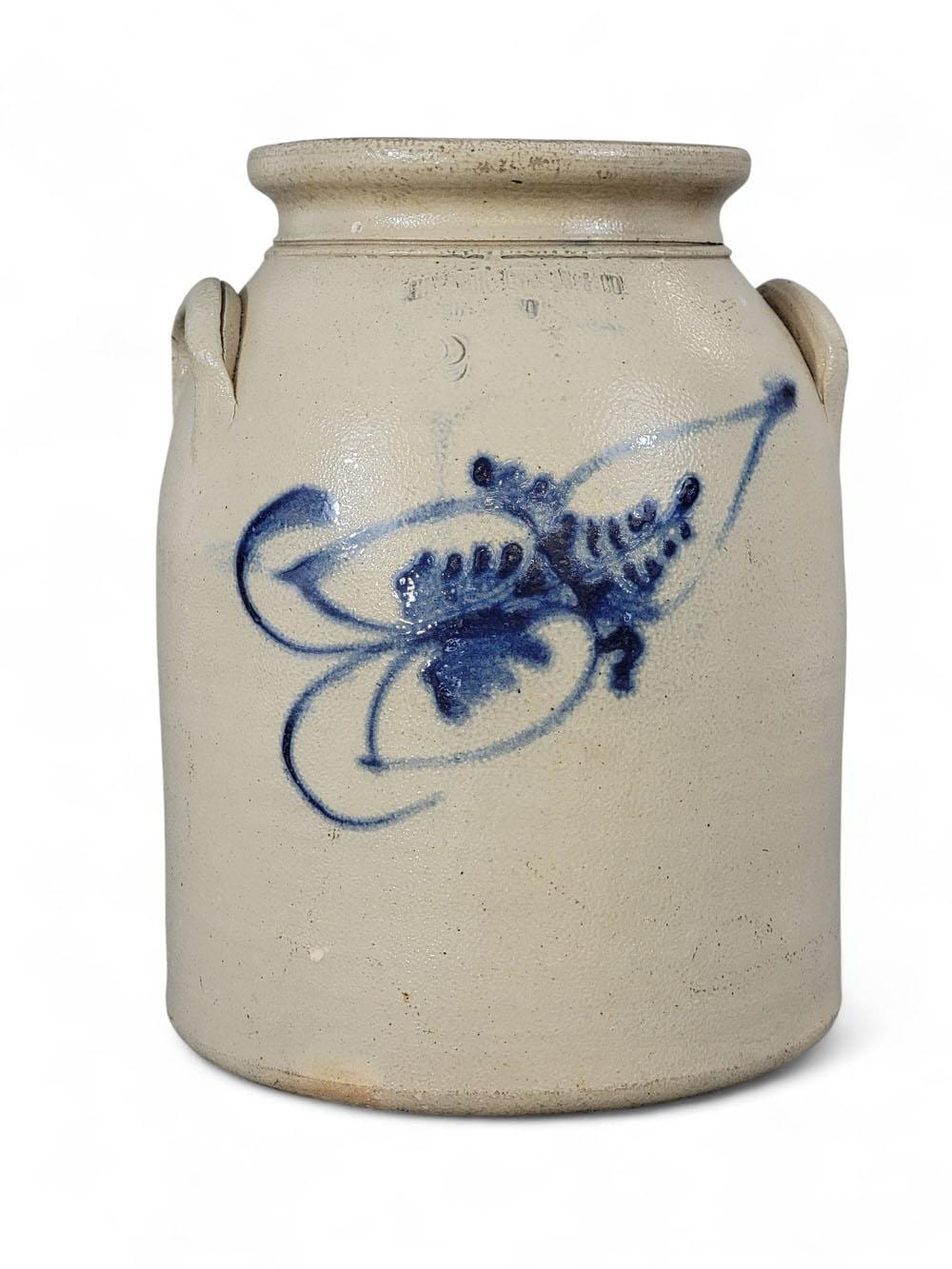 Cream-colored stoneware crock with two side handles and a blue floral bird decoration on the front.