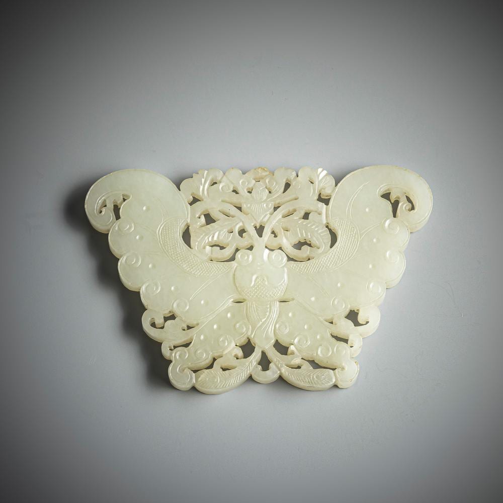 Light green jade pendant carved with a butterfly and leaf-like details, shown in a centered view against a gray background.