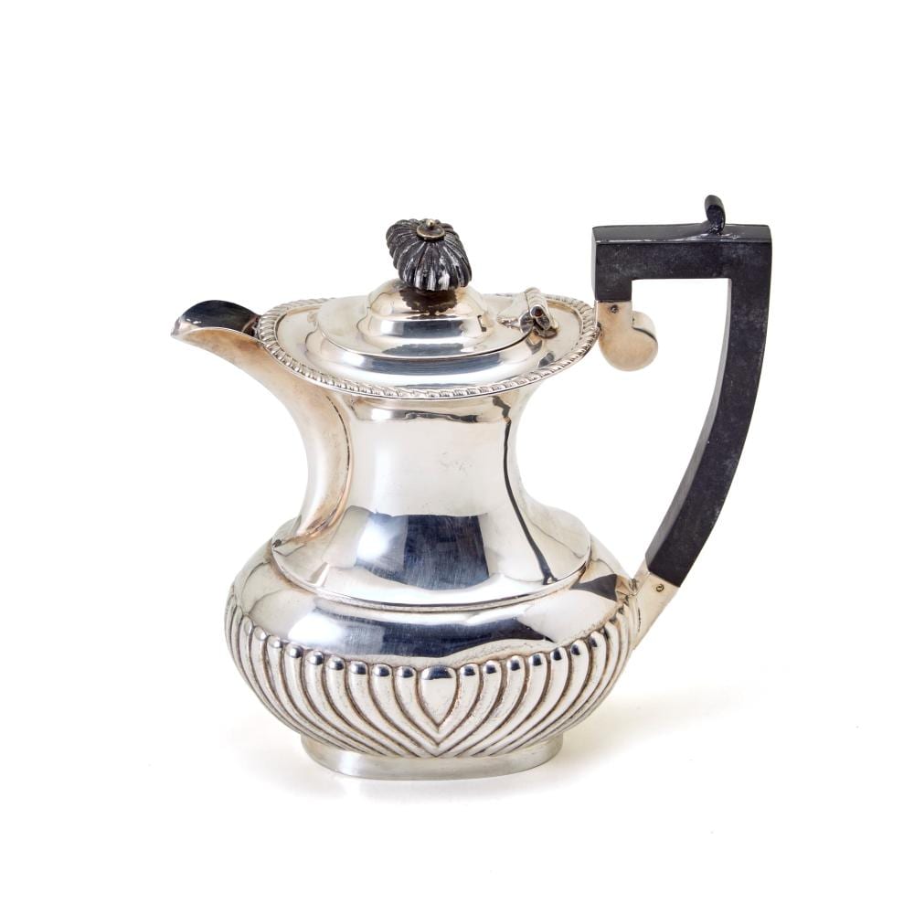 Silver teapot with engraved panel and ribbed base, domed lid knob, and curved handle.