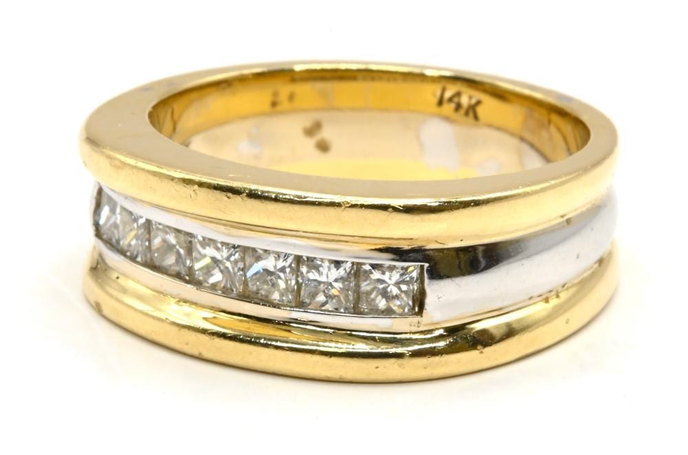 Close-up of a gold diamond wedding band ring with a row of clear rectangular-cut stones and an inner hallmark reading 14K.