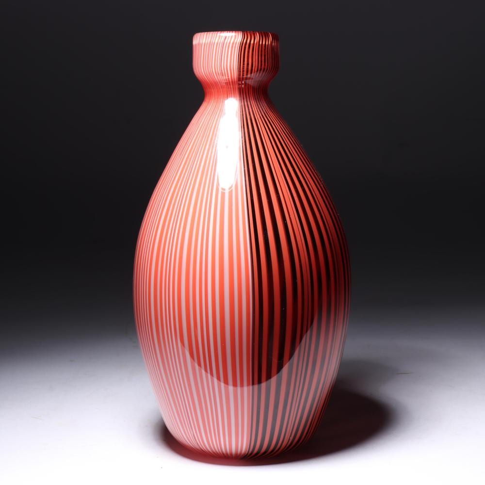 Red and white striped glass vase with a narrow neck and flared rim against a dark background.