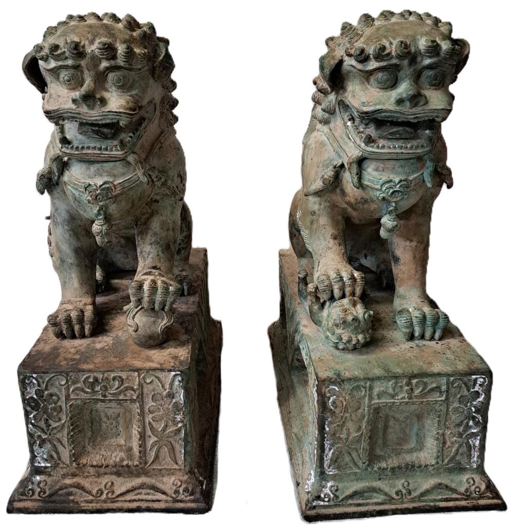 Pair of cast bronze guardian lion (foo dog) statues shown from two angles, with green patina and decorative pedestal bases.