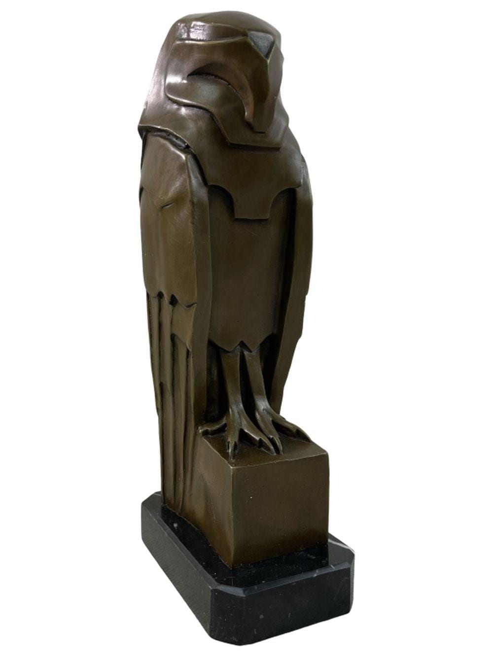 Bronze owl sculpture standing on a dark stone or marble base, shown in close-up from a side angle.