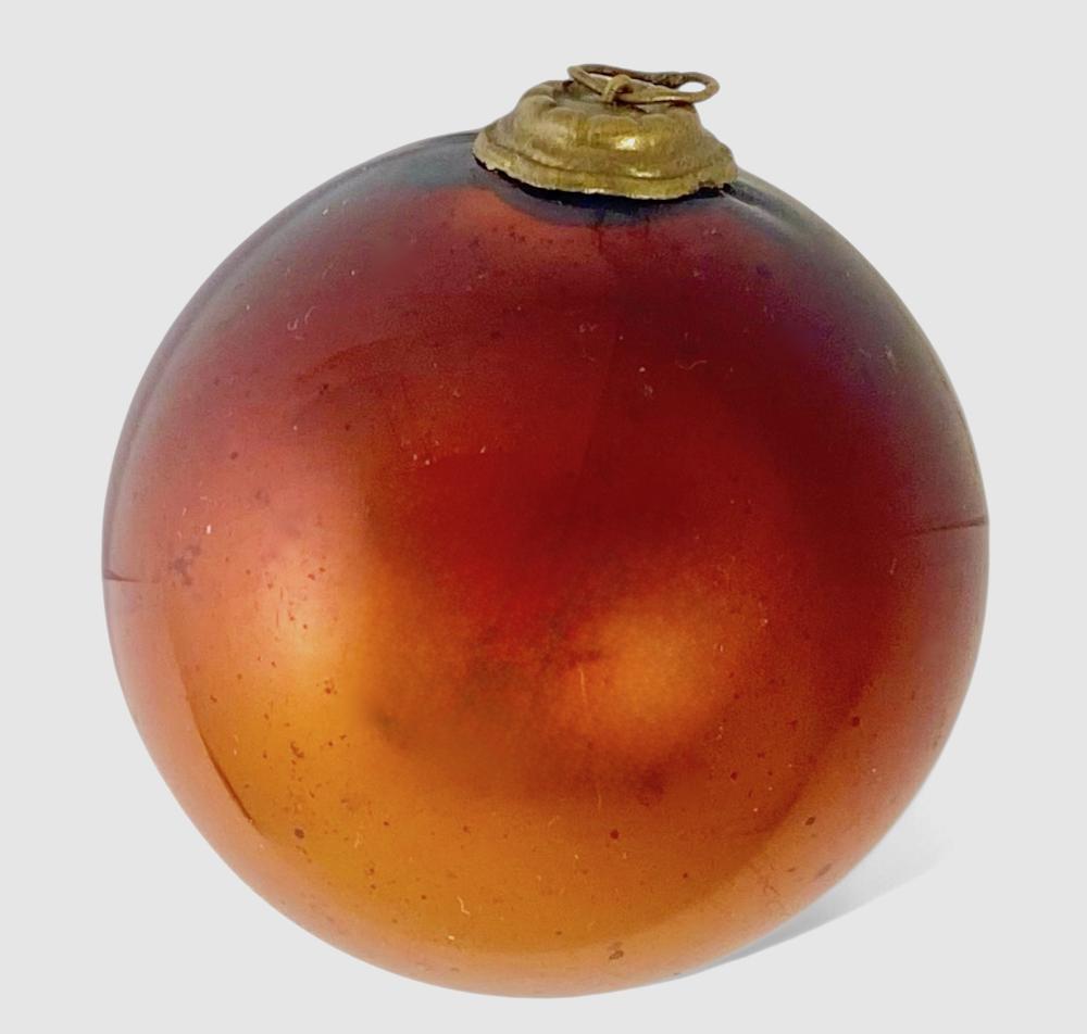 Glass Christmas ornament in a round kugel shape with a gold cap and loop hanger, featuring amber orange and red mottled color.