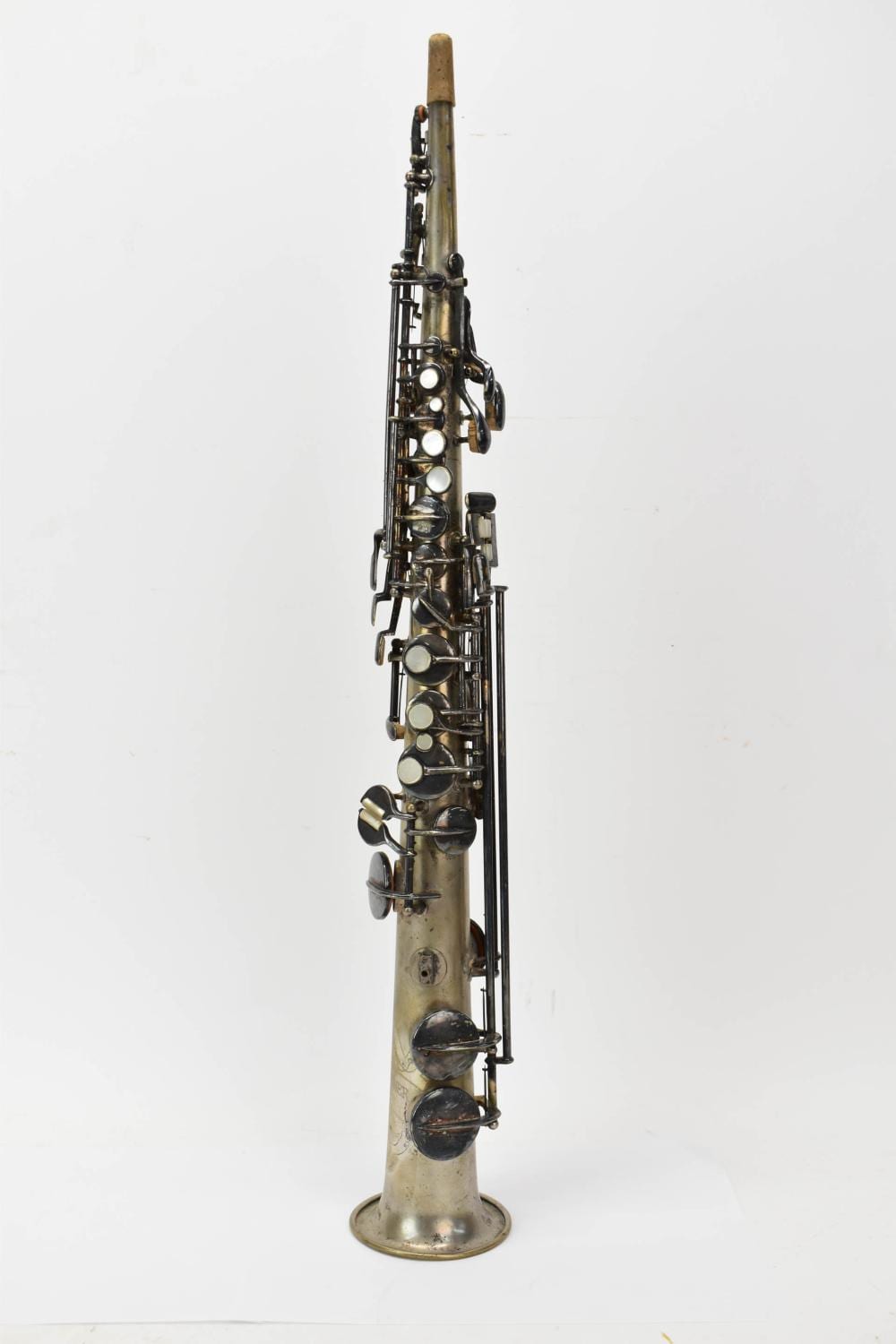 Full view of a brass saxophone standing upright on a round base, with visible keys and tone holes against a plain white background.