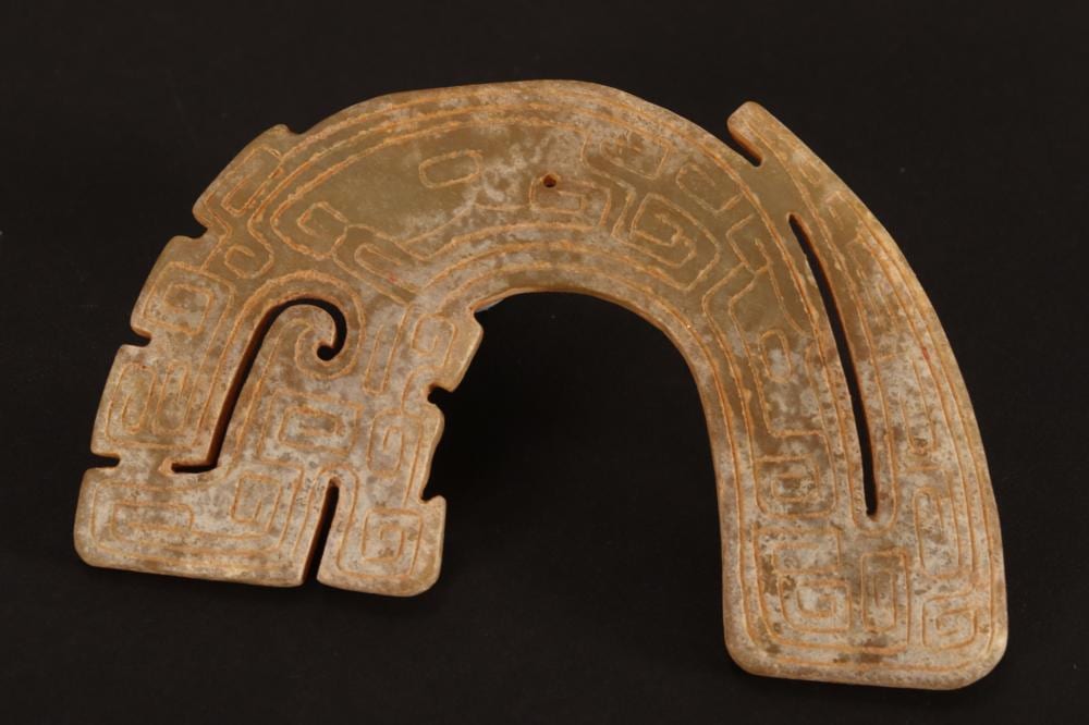 Carved jade-like ornament shaped like an arch with geometric patterning and a central cutout.